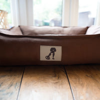 AllPetSolutions Dexter brown waterproof dog bed with a dog lying on it